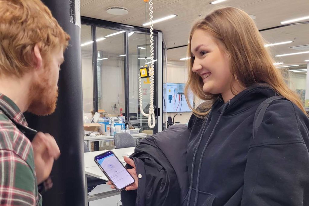 A student and the lab technician , Erno Vähänen, standing in a workshop environment. One of them is holding a phone, a Bitwards mobile access application in the screen. Students get access rights to the doors so they can freely get acquainted with the spaces. When the study progresses, they have to pass theory and practice tests to operate the machines.
