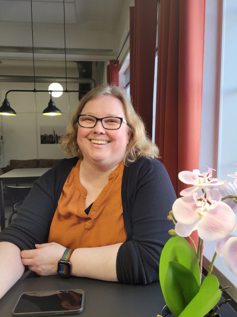 Jenni Mattila, responsible for sales at CatMarina, sits at a table with a big smile.
